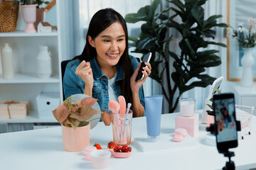 Young beautiful Asian reviewing cosmetic makeup and skin care collection, talking customer on...
