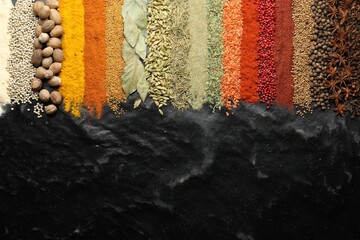 Many different spices on black table, flat lay. Space for text