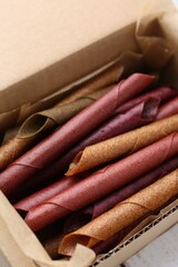 Tasty fruit leather rolls on white wooden table, above view