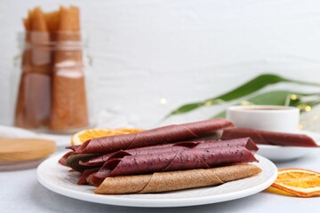 Tasty fruit leather rolls on white table. Space for text