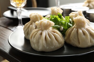 Delicious khinkali served with cilantro on wooden table, closeup