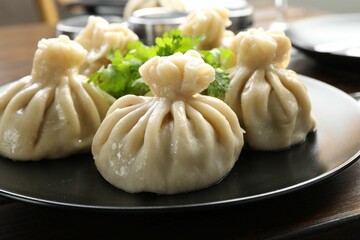 Delicious khinkali served with cilantro on wooden table, closeup