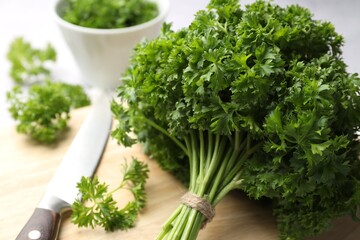 Fototapeta premium Fresh parsley and knife on light table, closeup