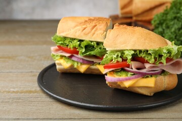 Pieces of tasty baguette sandwich with ham, cheese and vegetables on wooden table, closeup