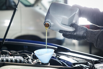 Worker pouring motor oil from canister into car engine, closeup