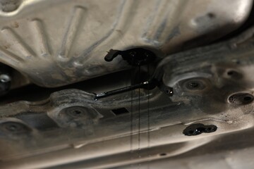 Dirty old motor oil dripping from car engine in workshop, closeup
