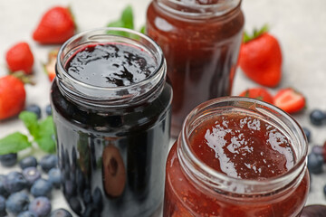 Different sweet jams in jars and ingredients on table, closeup