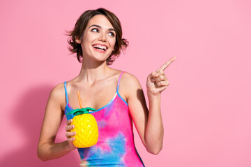 Young woman in summer fashion holding pineapple cup against pink background, radiating joy and...
