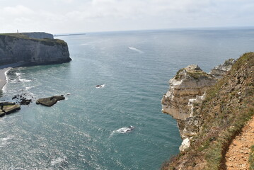 Vue de la mer du haut des falaises d'Étretat, sous un ciel bleu.