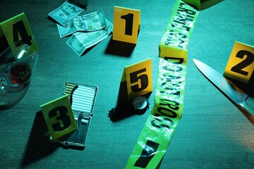 Obraz premium Forensic expertise. Crime scene with evidence, markers and police tape on wooden background, closeup. Color toned effect