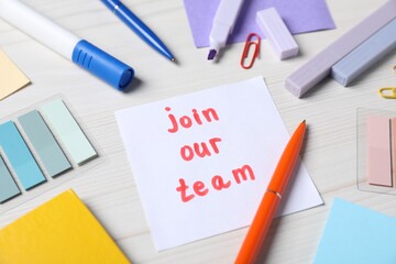 Paper note with phrase Join Our Team and stationery on white wooden table, closeup