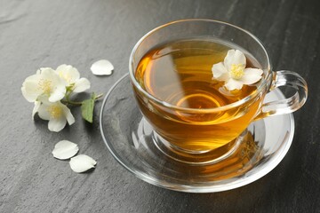 Aromatic jasmine tea and flowers on grey table, closeup