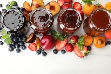 Different jams in jars and ingredients on white background, flat lay