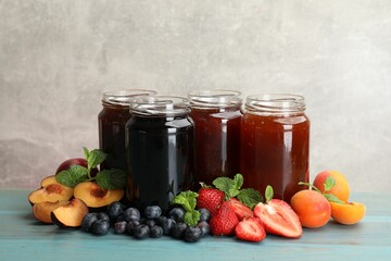 Different jams in jars and ingredients on blue wooden table. Space for text