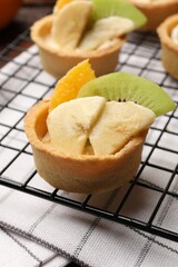 Tartlets with fruits and mint on table, closeup. Delicious dessert