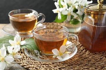 Aromatic jasmine tea in glass cups, flowers and teapot on table, closeup