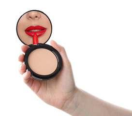 Beautiful woman looking in compact powder mirror while applying red lipstick on white background, closeup