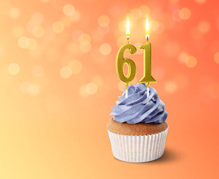 Yummy cupcake with burning number shaped candles on color gradient background with blurred lights, space for text. 61th birthday or other special occasion