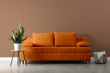 Stylish living room with comfortable sofa and pale brown wall. Interior design
