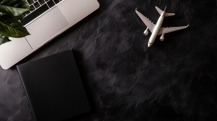 Passport, flight ticket, plane model and laptop on black table