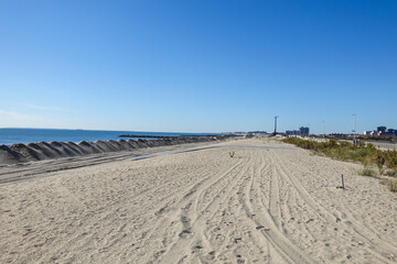 View along the ocean coastline empty beach with piles of sand near the ocean forming a man made dune