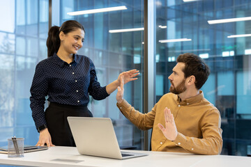 An office scene depicts a woman sexually advancing on an employee, but the man pushes her away in...