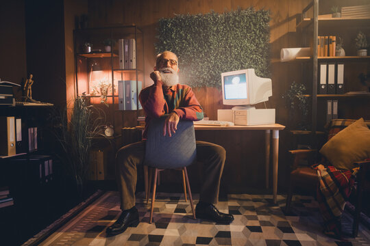 Elderly man in cozy home office working on vintage computer at night, symbolizing nostalgia and technological expertise