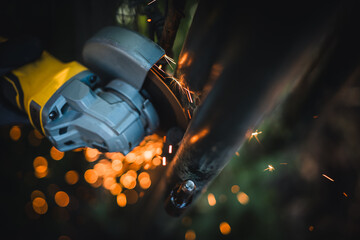 The hands of the master saw the metal with a grinder. Metal works in the workshop close up. Metal processing with angle grinder. Sparks in metalworking.