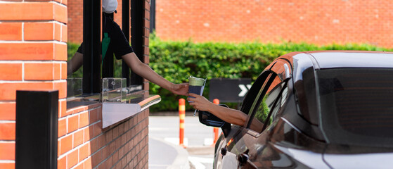 Naklejka premium Picking up coffee or water through a drive-thru during busy hours, a concept of efficient takeaway and fast service.