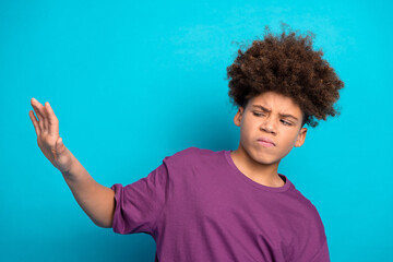 Young boy in casual tee making hand gesture against bright blue backdrop radiating youthful style and charm
