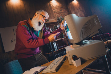 Elderly man enthusiastically engaging with vintage computer technology in a cozy home studio...