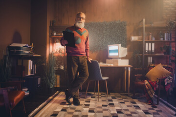Mature male working on a retro computer in a cozy home office setting surrounded by warm decor and...