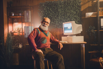 Elderly man in cozy office with vintage technology setup, expressing positivity and nostalgia...