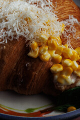 Macro croissant with creamy corn filling and parmesan cheese in blue bowl – elegant food presentation on rustic copper background