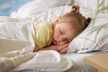 Peaceful adorable baby sleeping on a bed at home. Slumbering little child. Two years old girl sleeps peaceful at domestic room interior background. Serene dream. Cute face close up. Deep kid slumber