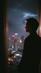 Person Gazing Thoughtfully at Nighttime City Skyline from a Window