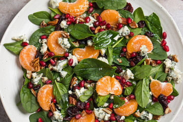 An appetizing festive salad of fresh spinach, tangerine, pomegranate and pine nuts on a plate. 