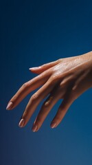Elegant Female Hand with Perfect Manicure Against a Smooth Blue Background