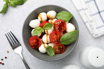 Tasty salad with mozzarella, tomatoes and basil served on light table, flat lay