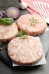 Fresh raw patties for burger and spices on grey table, closeup