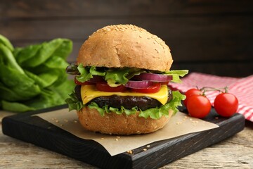 Delicious hamburger with patty and cheese on wooden table, closeup