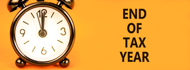 End of tax year symbol. Concept words phrase End of tax year on beautiful orange paper. Black alarm...