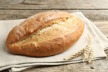 Loaf of bread and spikes on wooden table, closeup