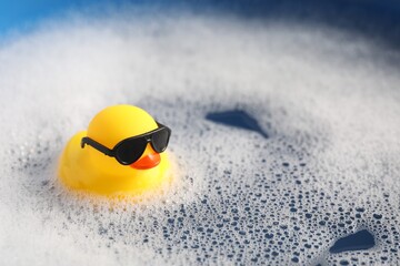 Obraz premium Cute rubber duck floating in water with bubbles against blue background, closeup
