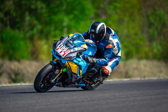  a person wearing a helmet and gloves, riding a 2018 BMW S1000RR on a race track surrounded by trees