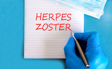 Herpes zoster symbol. Concept words Herpes zoster on beautiful white note. Doctor's hand in blue medical glove. Medical mask. Beautiful blue background. Medical healthy lifestyle herpes zoster concept