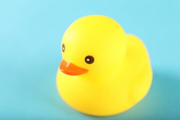 One cute rubber duck on light blue background, closeup. Space for text
