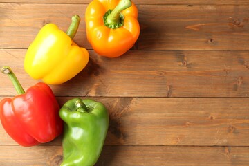 Ripe colorful bell peppers on wooden table, flat lay. Space for text