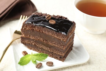 Piece of chocolate cake served with mint and fork on table, closeup