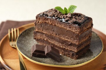 Piece of delicious chocolate cake with mint on table, closeup